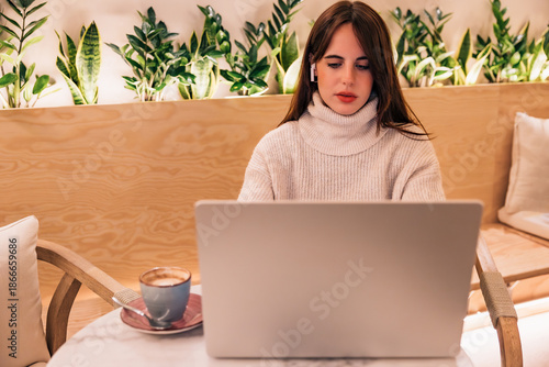 Young woman working remotely with laptop in cafe