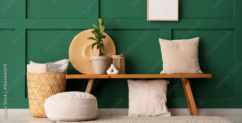 Φωτογραφία Wooden bench with pillows, wicker basket and houseplant near green wall in room