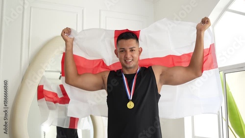 Young athlete celebrating with a medal and the English flag draped over his back