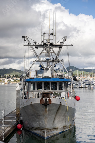 Off duty shrimping boat moored to the docks of the harbor under cloudy weather sky