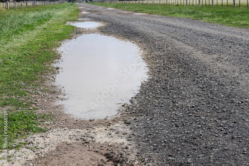 gravel road in the country with pot holes filled with water after rain