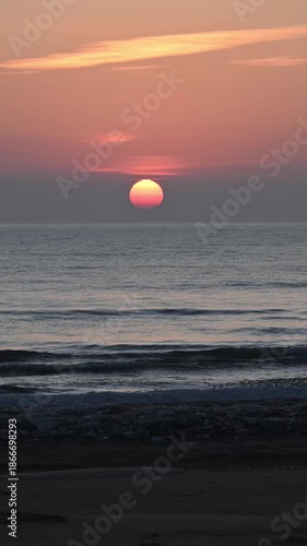 Winter sunrise over Lake Michigan with waves rolling in and an icy shoreline in the foreground. Vertical video taken along Lake Michigan at Point Beach State Forest, Manitowoc, Wisconsin.