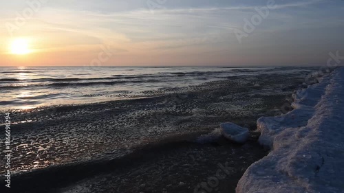 Waves from the icy waters of Lake Michigan splash along the frozen beach at sunrise.  Taken at Point Beach State Forest, Manitowoc County, Wisconsin.