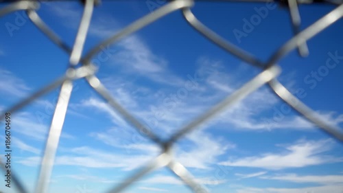 Looking Up Through a Chain Link Fence at Blue Sky and Clouds