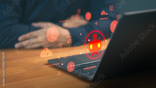Cybersecurity concept of AI bot error or system failure. Red warning icons and sad robot hologram on laptop screen representing technical glitch, data breach, and malware attack. © ParinPIX