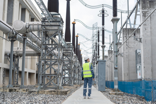 Foto Engineer walks through high voltage substation during routine patrol, visually inspecting equipment alignment and corridor safety to maintain stable and reliable power operations