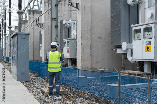 Canvas-taulu Electrical engineer performs outdoor substation inspection, checking control cabinets and equipment alignment to ensure operational safety, system stability, and maintenance compliance