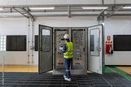 Bilde på lerret Engineer inspecting an indoor electrical control cabinet, reviewing panels and indicators, documenting operational status, ensuring safety compliance, and supporting preventive maintenance in power