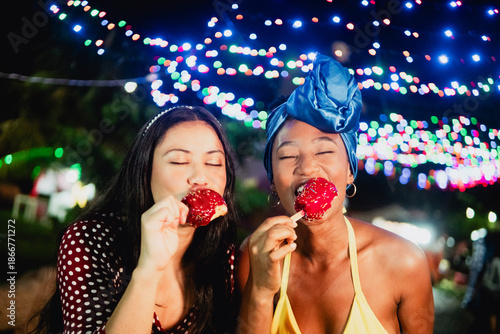 Diverse friends enjoying sweet candy apples at night market