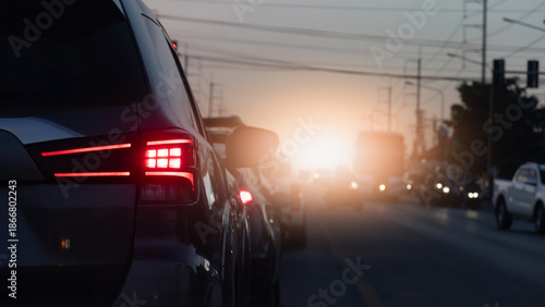 Rear side of car with red brake light on during traffic jam on the road at sunset. Rush hour transportation and driving safety concept.