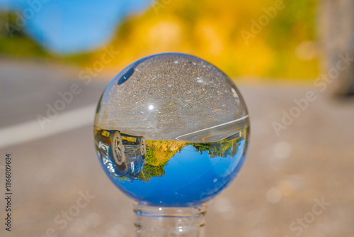 A clear crystal ball captures an inverted reflection of a serene landscape with blue sky and distant mountains, creating a surreal and artistic perspective. This image conveys creativity, vision