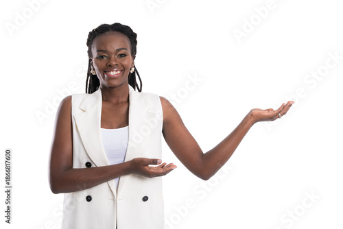 Smiling and confident black businesswoman in a white sleeveless blazer gesturing with open hand to present a product or idea at studio shot isolated on white background.