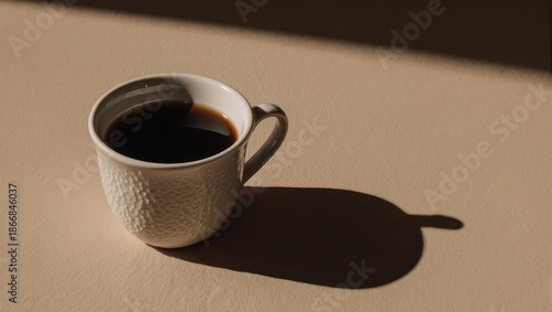 Elegant Coffee Cup on Beige Surface with Dramatic Shadow.