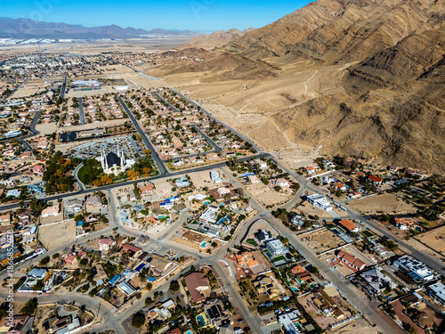 Aerial view of suburban residential neighborhood in Los Angeles desert area with intersecting streets, detached houses, swimming pools, dry landscapes, and low density urban planning seen from directl