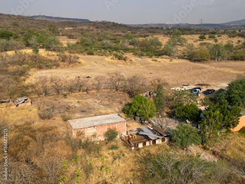 Aerial image of rustic buildings and surrounding vegetation in arid terrain of El Chilar community