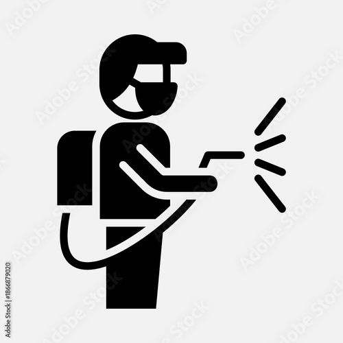 Black silhouette of a person in protective gear, including a mask and goggles, operating a backpack sprayer to disinfect an area.