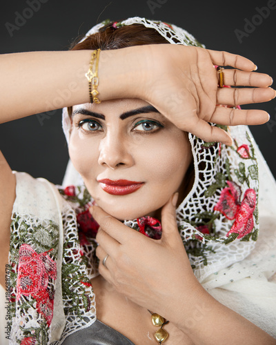 Studio close-up portrait of a woman wearing a floral scarf, highlighting beauty and confident eye contact.