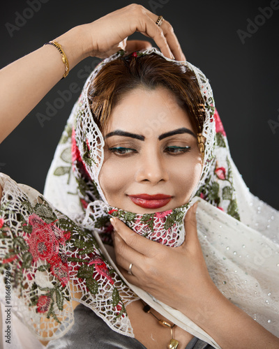 Studio close-up portrait of a woman wearing a floral scarf, highlighting beauty and a calm, graceful smile.