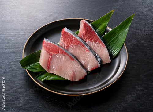 Fresh Japanese Yellowtail (Buri) Fillets on Black Plate over Dark Wooden Background