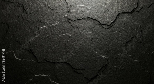 Dark textured black slate surface with prominent cracks and uneven layers dramatically lit from above