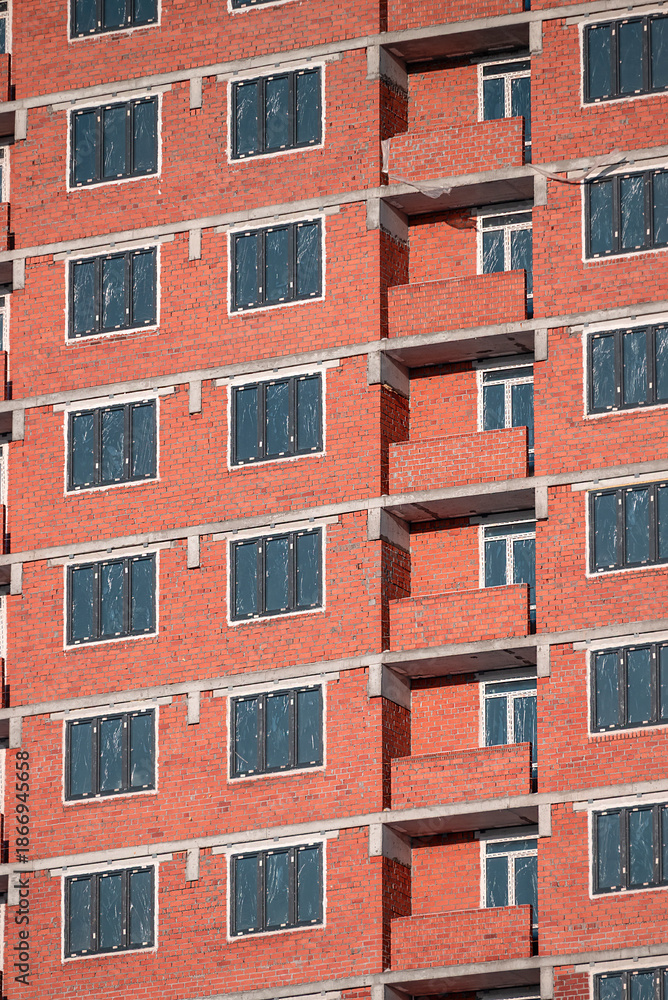 Obraz premium A fragment of the brick facade of a multi-storey residential building under construction on a winter day
