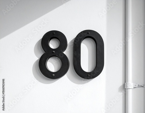 Black Number 80 Sign Mounted on Textured White Wall