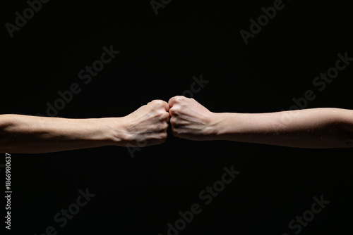 Wallpaper Mural Two fists meet in a firm fist bump, symbolizing unity, strength, or solidarity, set against a dramatic black background. Minimalist composition with strong contrast Torontodigital.ca