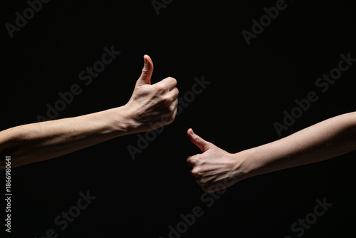 Wallpaper Mural Two extended arms give thumbs-up gestures toward each other, symbolizing approval, positivity, or agreement, against a dark background with strong contrast Torontodigital.ca