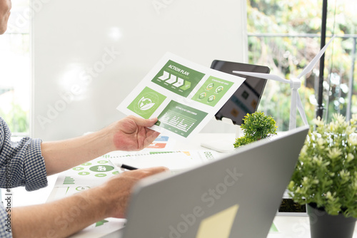 A diverse business team analyzing environmental charts and graphs in a collaborative meeting to create sustainable strategies in a modern office.