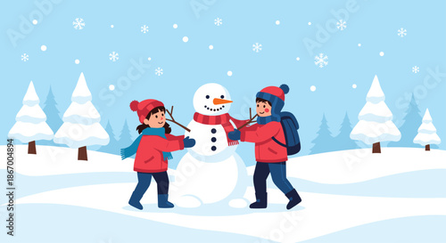 Two happy children in warm winter clothes building a snowman together in a snowy forest landscape with falling snow.