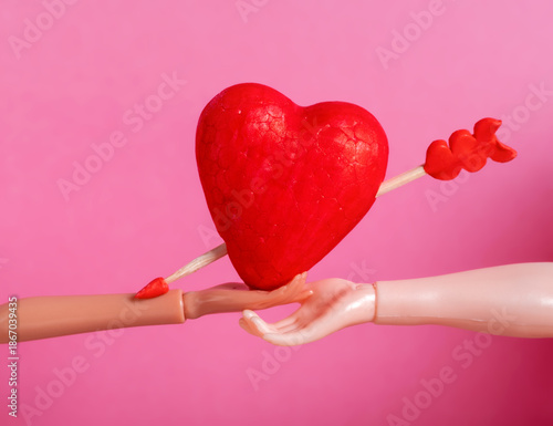 Mannequin Hands Holding Red Heart with Arrow on Pink Background