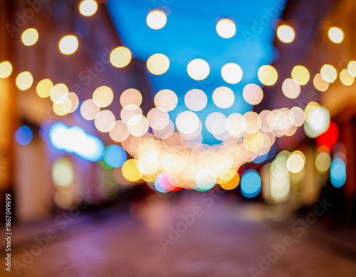 Festive string lights and city illuminations create a magical bokeh effect, blurring into colorful circles of light along a vibrant urban street at night.