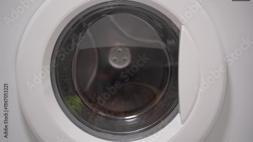 Foamy soap suds churning around shoes in washing machine drum, creating dynamic bubble patterns. Dense white foam envelops footwear during intense cleaning cycle.