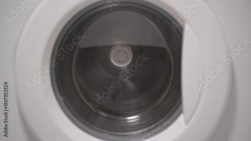 Foamy soap suds churning around shoes in washing machine drum, creating dynamic bubble patterns. Dense white foam envelops footwear during intense cleaning cycle.