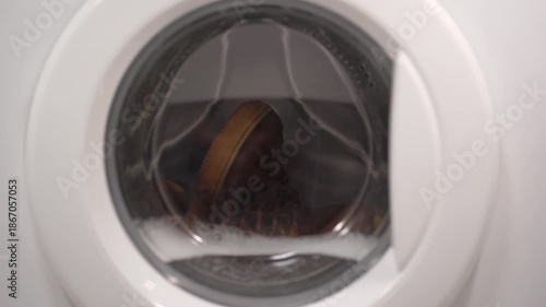 Foamy soap suds churning around shoes in washing machine drum, creating dynamic bubble patterns. Dense white foam envelops footwear during intense cleaning cycle.