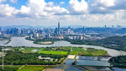 Aerial view of a modern city with a river and green fields.