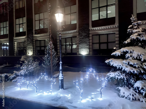 Snowy courtyard with glowing star light decorations and street lamp at night creating calm festive winter scene and peaceful holiday atmosphere