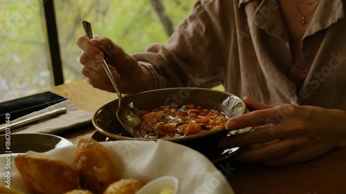 A close-up of a female hand gently stirring minestrone soup with a spoon in a restaurant setting. Perfect 4K video for food ads, restaurant promos, and culinary content.