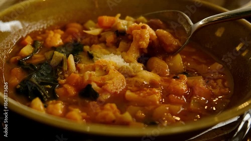 A close-up of hot minestrone soup gently stirred with a spoon to cool it down. Perfect 4K video for food ads, restaurant menus, and culinary content.