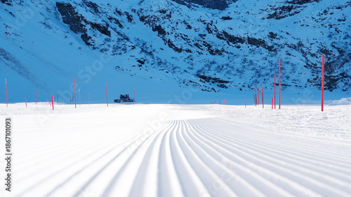 Photography Groomed ski slope with corduroy snow texture, featuring bright pink markers, sho