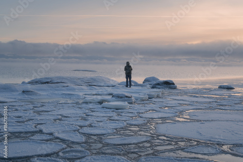 A man stands on the coast of a freezing sea