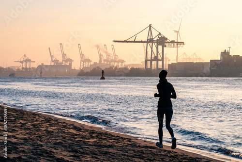 A jogger at the beach at the Elbe River in Hamburg at sunrise
