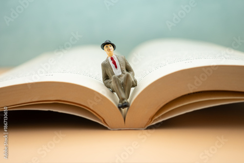 Foto Small figure sits on open book with plain background and soft lighting during in