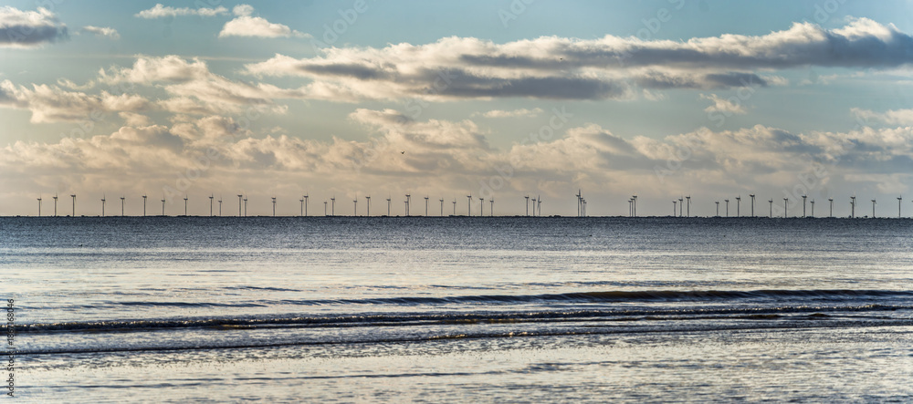 Obraz premium Tranquil Seaside Horizon With Offshore Wind Turbines Under a Cloudy Blue Sky, Blaavand, Denmark