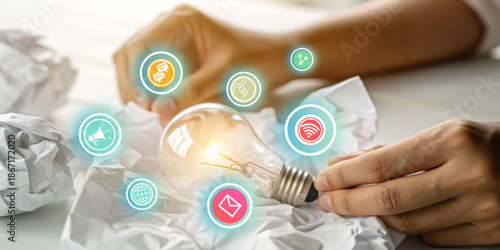 Creative Marketing Strategy. Hand holding a light bulb against a crumpled paper background with the concept of doing business through wireless internet technology