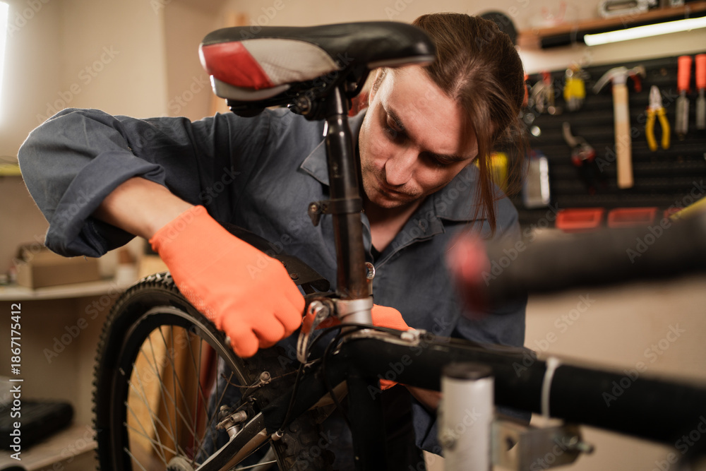 Obraz premium Bike service, repair and upgrade concept. Male Cycling mechanic fixing bicycle seat working in garage. cycle repairman in workshop.