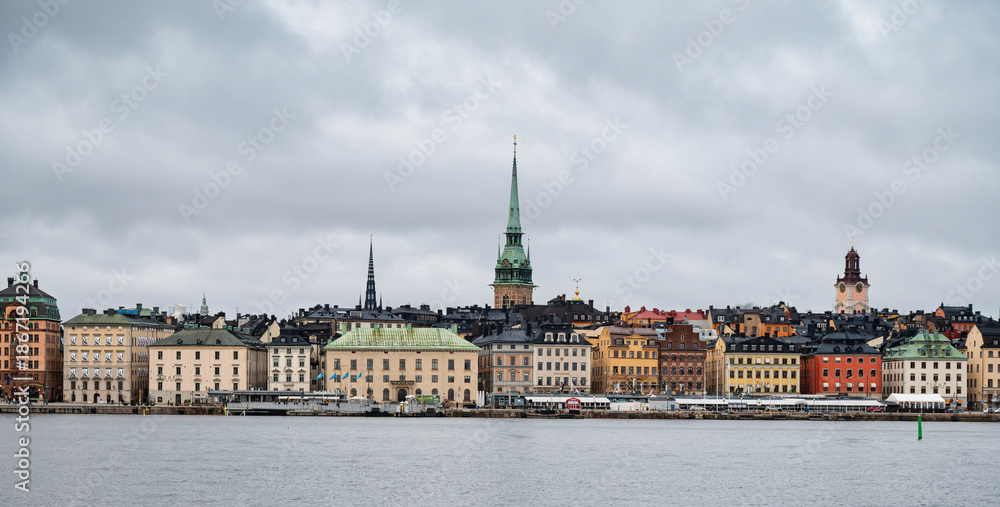 Fototapeta premium Panoramic view of Stockholm cityscape with colorful historic buildings and cloudy sky across the water