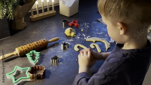 Top view of a boy making cookies from shortcrust pastry, Christmas themed bake at home 