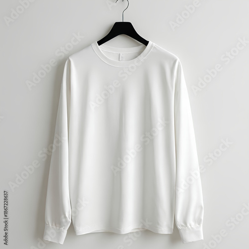 White long sleeve shirt hanging on black hanger against plain white background, showcasing smooth fabric and simple design for casual or formal wear