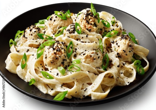 Creamy pasta with meatballs, topped with sesame seeds and scallions